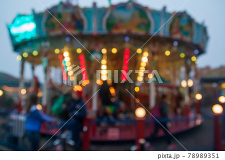 A blurry colorful carousel in the amusement park at evening illumination. The effect of bokeh A blurry colorful carousel in the amusement park at evening illumination. The effect of bokeh 78989351