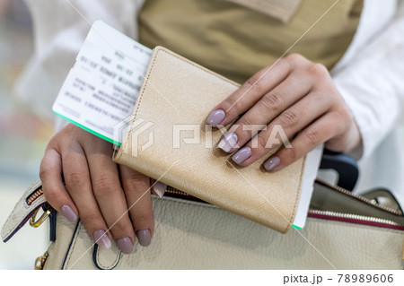 Closeup female tourist hands checking documents, passport and ticket get ready boarding at airport Closeup female tourist hands checking documents, passport and ticket get ready boarding at airport 78989606
