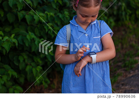Kid using smartwatch outdoor. Child talking on the smartphone. Schoolgirl using touchscreen on watches browsing internet Kid using smartwatch outdoor. Child talking on the smartphone. Schoolgirl using touchscreen on watches browsing internet 78990636