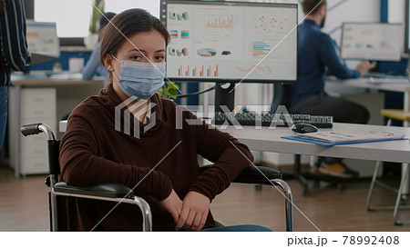 Woman employee with disabilities with protection mask looking at camera 78992408