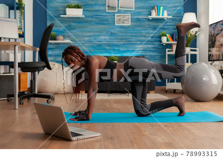 Black woman doing straight- leg donky kick pushing left foot up 78993315