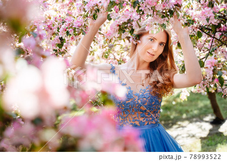 Red-haired woman on a background of pink flowers. 78993522