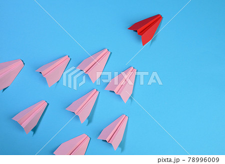 a group of pink paper planes follow the first red against a blue background 78996009