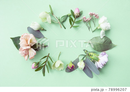 Floral frame with pink roses, white flowers, branches, leaves and petals on green background. Flat lay, top view 78996207