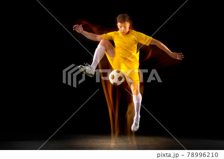 One caucasian male football or soccer player training with ball in mixed light isolated on dark background. Concept of professional sport, active, motion. 78996210