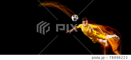 Flyer. One caucasian male football or soccer player training with ball in mixed light isolated on dark background. Concept of professional sport, active, motion.. 78996223