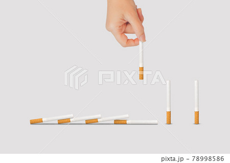 Hand holding and taking out cigarette piece from the row of cigarettes. Hand holding and taking out cigarette piece from the row of cigarettes. 78998586