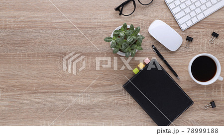 Top view wooden workspace office desk with computer and office supplies. Flat lay work table with blank notebook, keyboard, green leaf, pen and coffee cup. Copy space for your advertising content. Top view wooden workspace office desk with computer and office supplies. Flat lay work table with blank notebook, keyboard, green leaf, pen and coffee cup. Copy space for your advertising content. 78999188