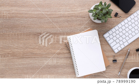 Top view wooden workspace office desk with computer and office supplies. Flat lay work table with blank notebook, keyboard, green leaf, pen and coffee cup. Copy space for your advertising content. Top view wooden workspace office desk with computer and office supplies. Flat lay work table with blank notebook, keyboard, green leaf, pen and coffee cup. Copy space for your advertising content. 78999190