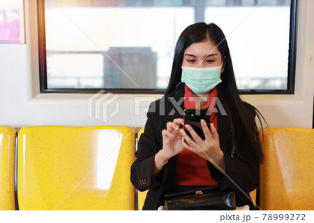 New normal covid-19 epidemic, young business asian woman wearing mask protection for prevent virus covid-19 or coronavirus infection from people in train, using smartphone communication in train 78999272