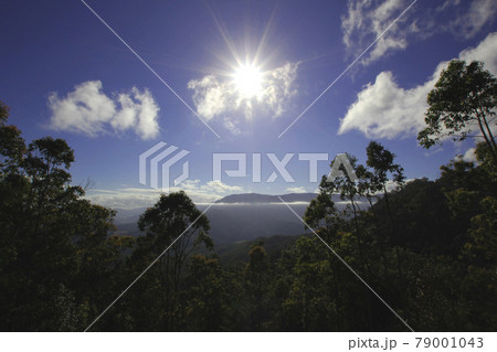 爽快な快晴の空:強い光を放つサンバーストと山頂に広がる美しい雲の風景 爽快な快晴の空:強い光を放つサンバーストと山頂に広がる美しい雲の風景 79001043