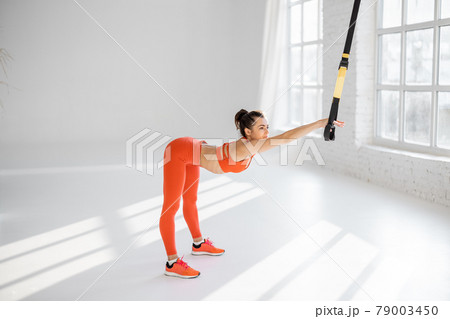 Woman training on TRX fitness straps 79003450