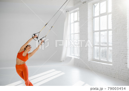Woman training on TRX fitness straps Woman training on TRX fitness straps 79003454