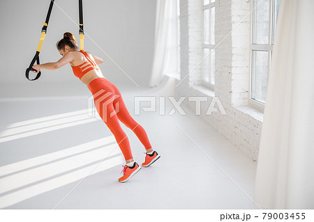 Woman training on TRX fitness straps Woman training on TRX fitness straps 79003455