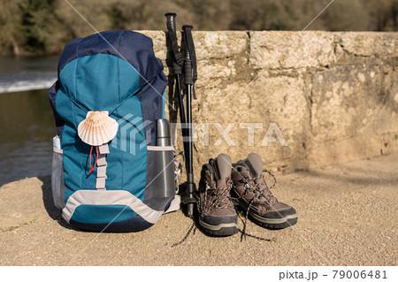 Backpack with seashell symbol of Camino de Santiago, trekking boots and poles leaning on stone wall. Pilgrimage to Santiago de Compostela. Copy space Backpack with seashell symbol of Camino de Santiago, trekking boots and poles leaning on stone wall. Pilgrimage to Santiago de Compostela. Copy space 79006481