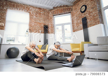 Retired couple using laptop while doing stretching exercises Retired couple using laptop while doing stretching exercises 79006573