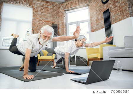 Elderly couple using laptop for doing yogat at home 79006584