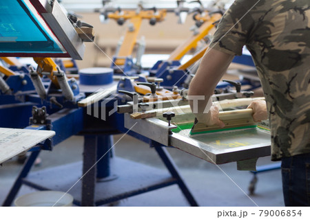 Serigraphy silk screen print process at clothes factory. Frame, squeegee and plastisol color paints Serigraphy silk screen print process at clothes factory. Frame, squeegee and plastisol color paints 79006854