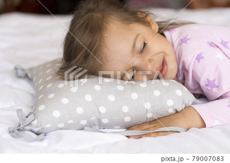 home, comfort, childhood, care, love, sweet dream- little pretty smiling happy authentic toddler sibling kid child girl in pajamas lie rest sleep on bed pillows with closed eyes soft cozy sleepy mood 79007083