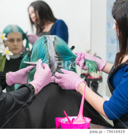 Process of hair dyeing in beauty salon. Two hairdressers applying paint to hair during bleaching hair roots 79016929