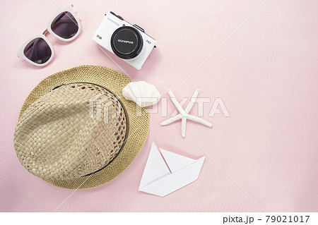 Flat lay traveler accessories on pastel pink background with small white camera, sunglasses, straw hat. Top view travel or vacation concept with copy space 79021017