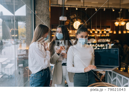Three businesswomen with their face masks debating different views on work 79021043