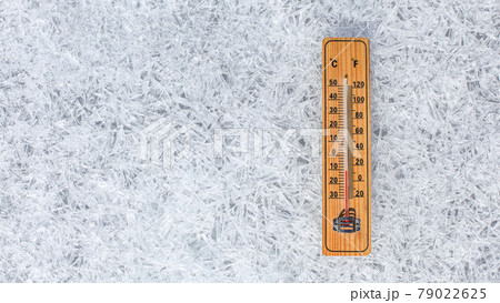 Wooden thermometer showing low temperature laying on flat ice ground made of crystals. Winter weather concept. Wooden thermometer showing low temperature laying on flat ice ground made of crystals. Winter weather concept. 79022625