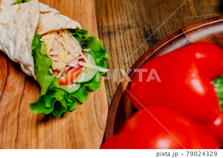 Bell Peppers and pita roll with vegetables and cheese on a wooden cutting board 79024329