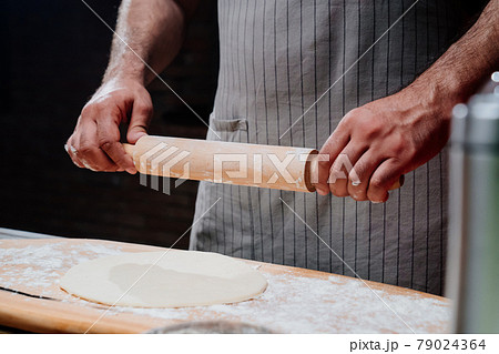 hands roll the dough into a thin layer. Cooking pizza, noodles or pitta at home 79024364