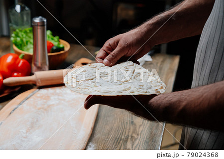 men's hands hold a thin flatbread. Cooking pizza, noodles or pitta at home men's hands hold a thin flatbread. Cooking pizza, noodles or pitta at home 79024368