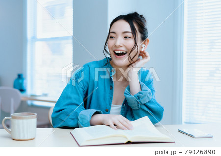 リビングで音楽を聴きながら読書をする若い女性 リビングで音楽を聴きながら読書をする若い女性 79026890