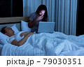 Woman sitting on bed in the night and using laptop computer 79030351