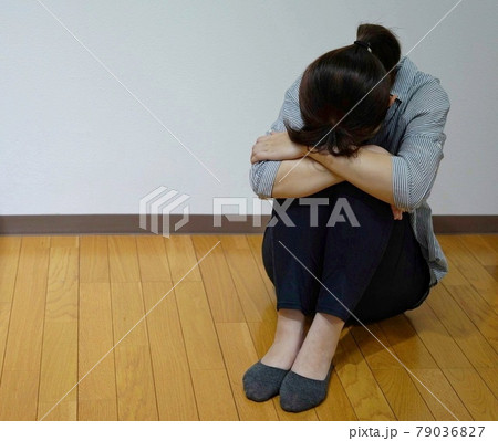 部屋で膝を抱えてふさぎ込んでいる女性のイメージ 部屋で膝を抱えてふさぎ込んでいる女性のイメージ 79036827