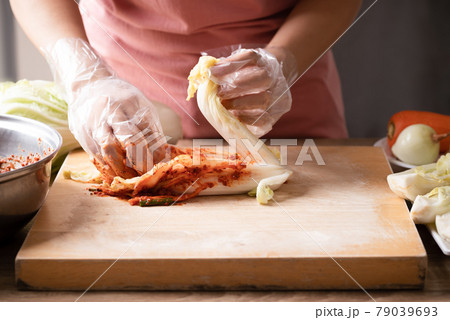 Woman making kimchi cabbage on wooden board, Popular homemade Korean food Woman making kimchi cabbage on wooden board, Popular homemade Korean food 79039693