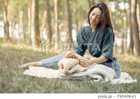 Girl sitting in a summer park and knitting Girl sitting in a summer park and knitting 79040641