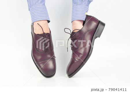Classic brown shoes worn on the hands on a white background 79041411