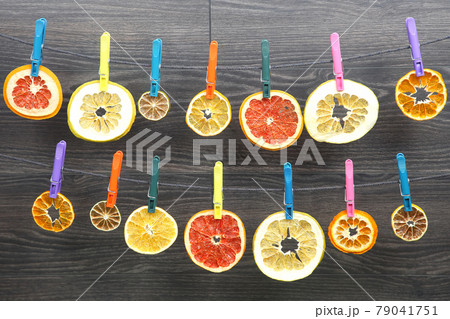 dried pieces of citrus fruits hang on clothespins 79041751