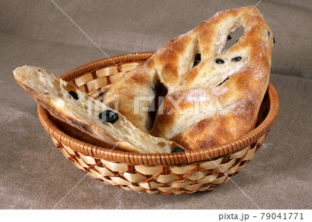 white bread stuffed with olives lies in a straw basket on gray linen tablecloth 79041771