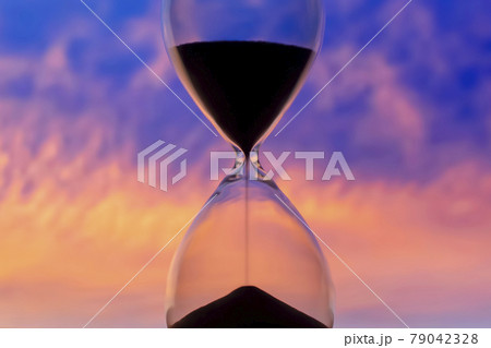 Hourglass on the background of a sunset sky. The value of time in life. An eternity. Hourglass on the background of a sunset sky. The value of time in life. An eternity. 79042328