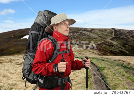 equipped with traveler in a red jacket with Hiking poles looks into the distance 79042767