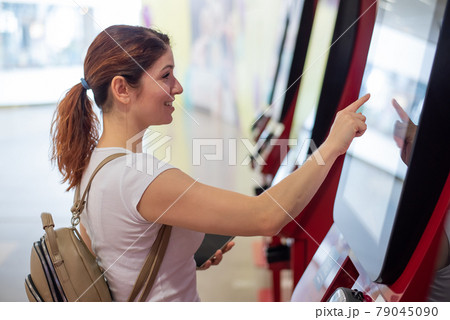 Woman uses a self-checkout counter in a shopping mall. Woman uses a self-checkout counter in a shopping mall. 79045090
