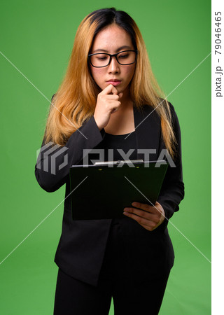 Portrait of young Asian businesswoman against green background 79046465