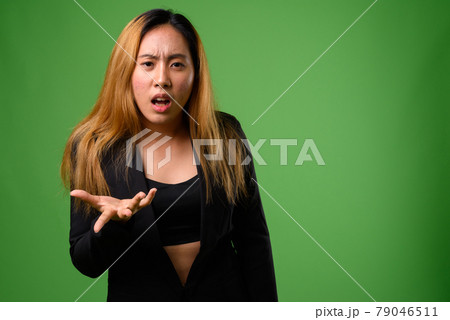 Portrait of young Asian businesswoman against green background Portrait of young Asian businesswoman against green background 79046511