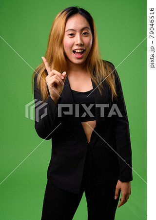 Portrait of young Asian businesswoman against green background Portrait of young Asian businesswoman against green background 79046516