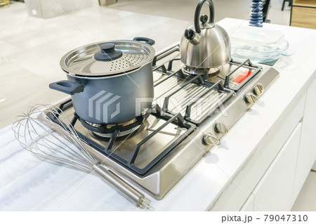 Close-up of stainless steel cooking pot and kettle boiling on gas stove in contemporary modern home kitchen. Selective focus on pot. 79047310