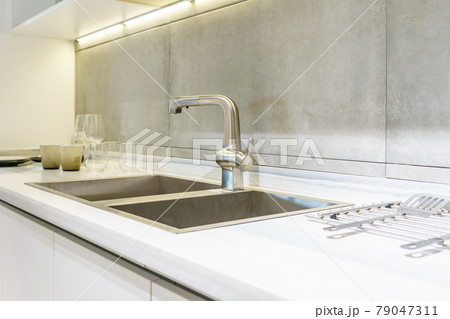 Stainless kitchen sink and Tap water in the kitchen. The interior of the kitchen room of the apartment. Built-In Appliances. Kitchen Appliance. Domestic Appliances 79047311