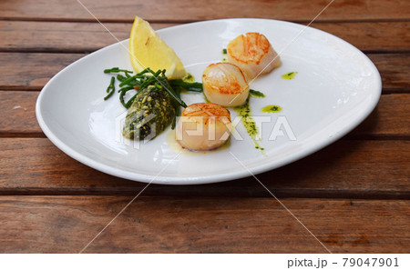 Portion of grilled scallops on plate on table Portion of grilled scallops on plate on table 79047901