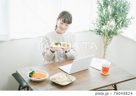 デリバリーフードを食べながらテレワークする女性 79049824