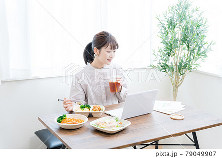 デリバリーフードを食べながらテレワークする女性 79049907
