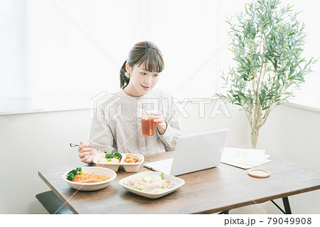 デリバリーフードを食べながらテレワークする女性 79049908